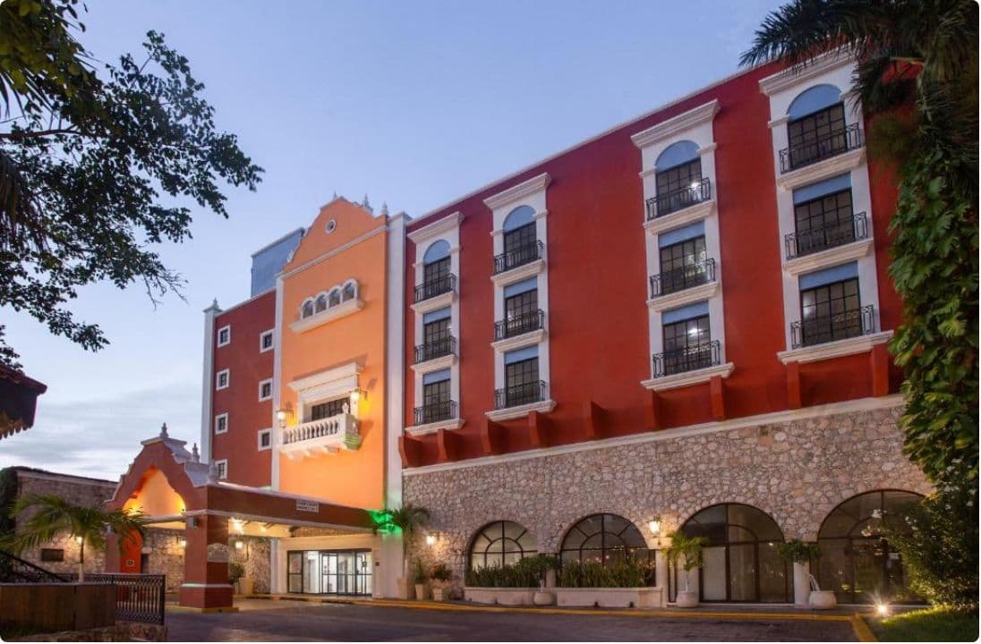 Fachada del Holiday Inn Mérida iluminada al atardecer